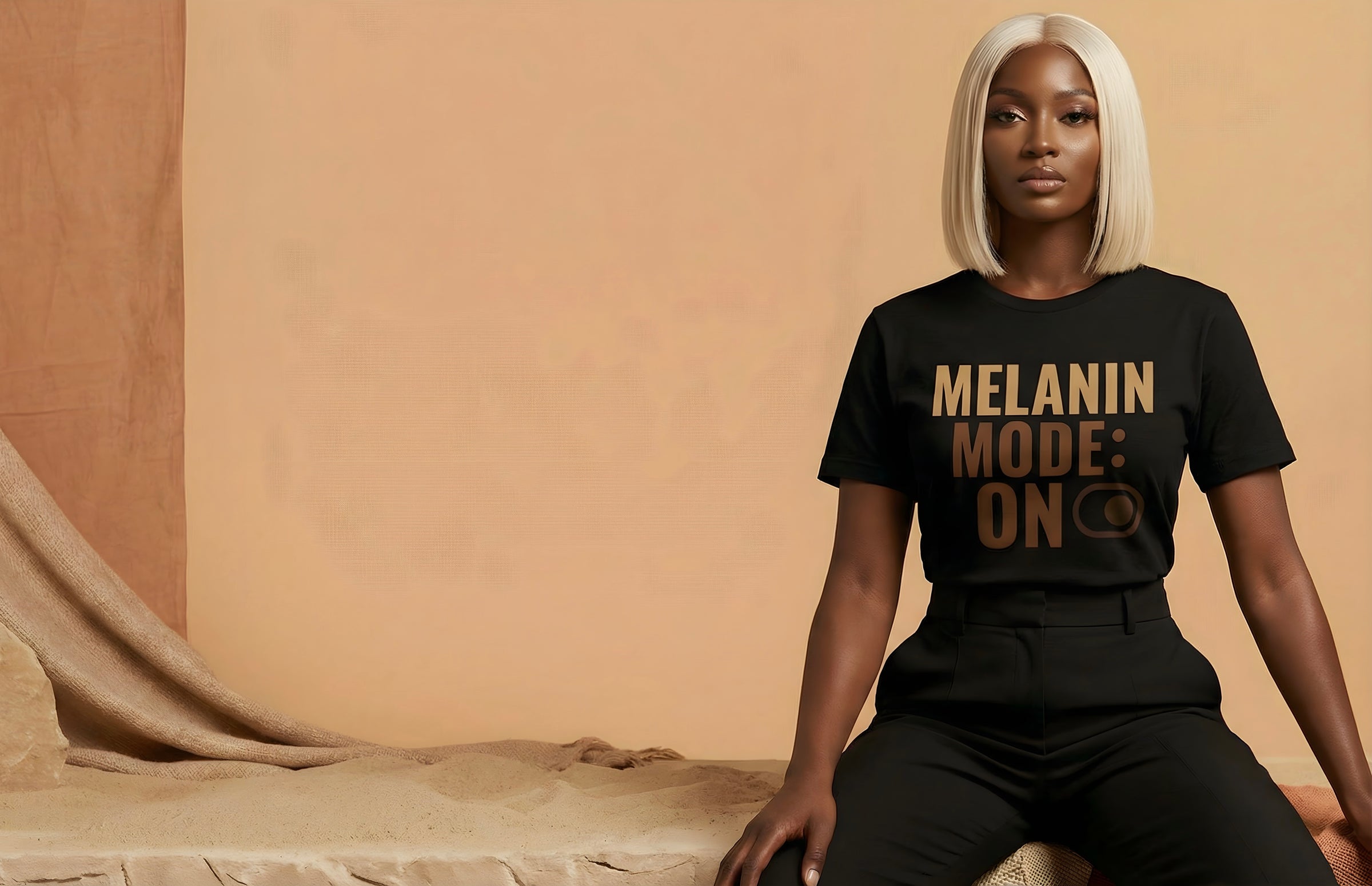 Black woman wearing a black Statement Tee t-shirt with 'Melanin Mode: On' text in a warm-toned room.
